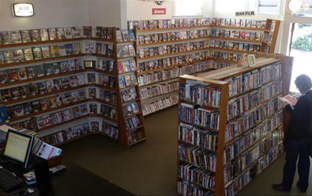 A person is browsing dvds in a video store in one of the last standing video stores in Aotearoa